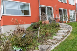 Un bâtiment rouge avec un jardin et un chemin qui mène à une porte.