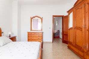 Une chambre à coucher comprenant un lit, une commode, une armoire et un miroir.