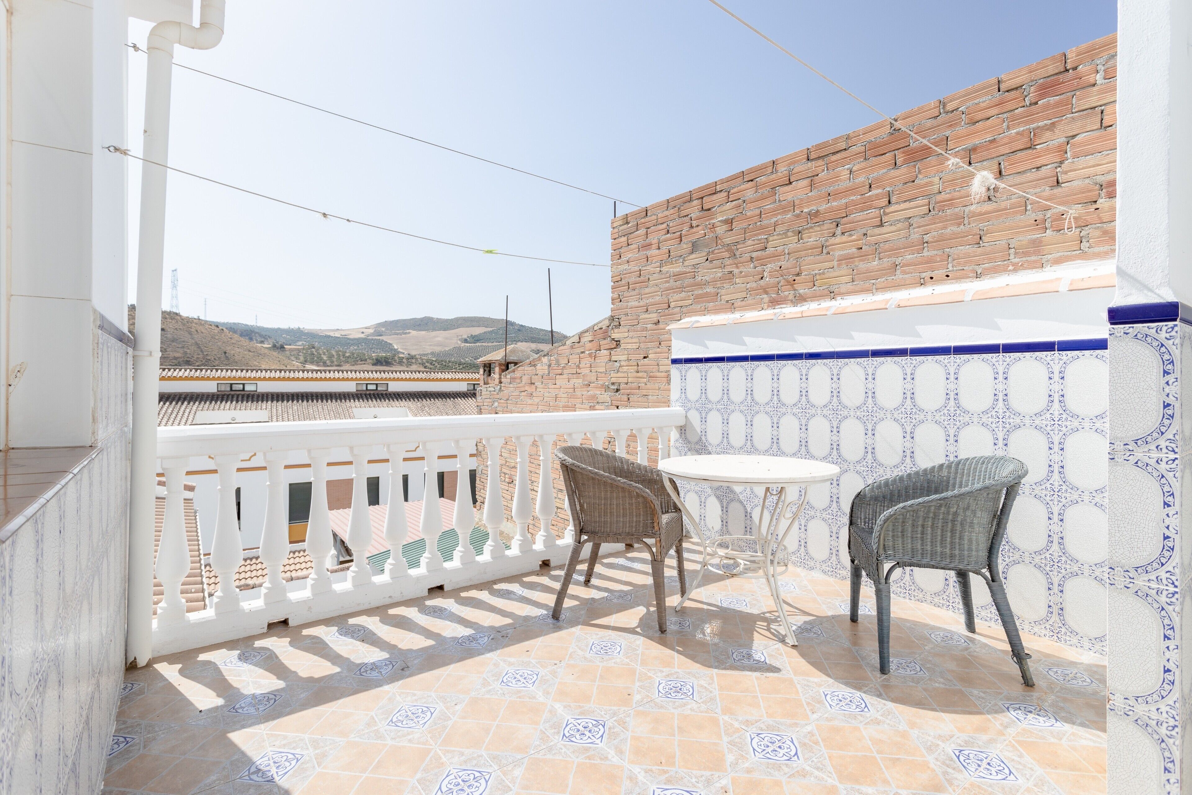 A balcony with a white railing, two wicker chairs, and a small round table.