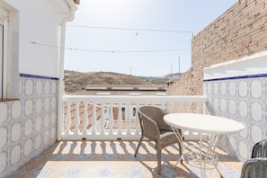 A balcony with a white railing, a wicker chair, and a small round table.
