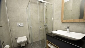 Een moderne badkamer met een douchecabine van glas, een wit toilet en een zwart aanrecht met een witte wasbak.