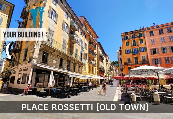 A bustling street scene in Place Rossetti with outdoor cafes and pedestrians.