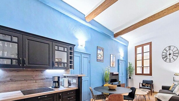 A modern kitchen with dark cabinets, a wooden countertop, and a dining area with a round table and chairs.