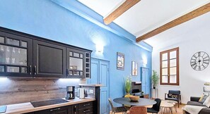 A modern kitchen with dark cabinets, a wooden countertop, and a dining area with a round table and chairs.