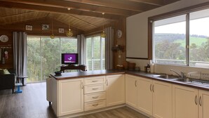 A modern kitchen with wooden beams, a large window, and a television.