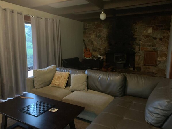 A living room with a stone fireplace, a sofa, and a chessboard on a table.