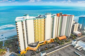 A high-rise hotel with multiple floors, a parking area, and a view of the ocean. - GORGEOUS DIRECT OCEANFRONT CONDO MYRTLE BEACH - PET FRIENDLY GREAT VIEWS !! (Myrtle Beach)