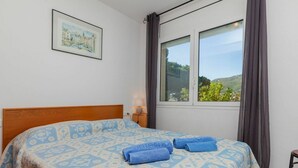 A bedroom with a bed, a window with curtains, a bedside lamp, and a framed picture on the wall. - Stunning  villa for 6 people with WIFI, TV, patio, pets allowed and panoramic view (Llançà)