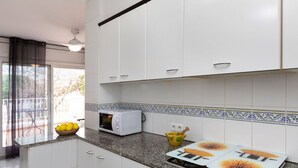 A modern kitchen with white cabinets, a microwave, a gas stove, and a decorative backsplash. - Stunning  villa for 6 people with WIFI, TV, patio, pets allowed and panoramic view (Llançà)