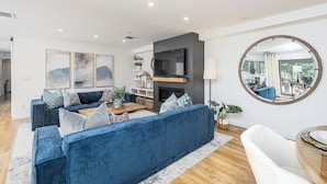 Un salon moderne avec un canapé bleu, un téléviseur à écran plat et un miroir rond.