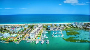 An aerial view of a coastal resort with multiple buildings, a marina with boats, and a beach. - Marlin Quay 311, two bedroom, two bathroom, channel views (Garden City Beach)