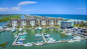 Un puerto deportivo con varias embarcaciones amarradas, un hotel de varios pisos y balcones, y una vista despejada del océano.