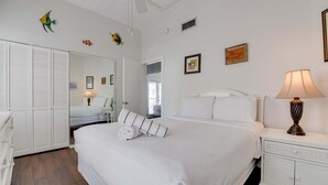 A neatly arranged bedroom with a bed, bedside table, lamp, and a wardrobe. - Parking & Shared Pool - Casa Key West (Key West)