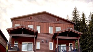 Ein zweigeschossiges Holzhaus mit Garage, Steinverkleidungen und einem Balkon.