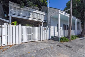 A two-story house with a white picket fence, a covered porch, and a garage. - Traveler's Palm - Studio Near Duval Street (Key West)