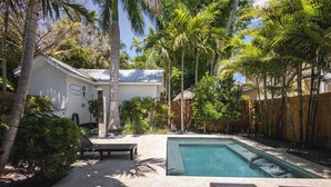 Un jardin avec une piscine, des chaises longues et une clôture en bois.