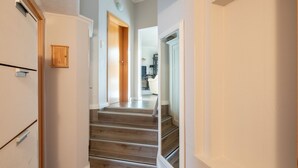 A hallway with a wooden staircase leading to a room with a white door.