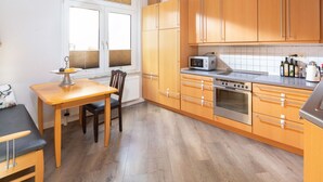 A compact kitchen with wooden cabinets, a built-in oven, and a microwave.