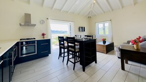 A modern kitchen with a central island, a dining area with a table and chairs, and a view of the outdoors. - One Bedroom Apartment within walking distance of English Harbour (English Harbour)
