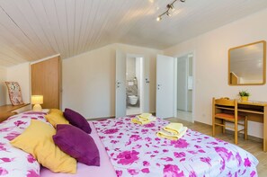 A bedroom with a bed, a desk, and a mirror.