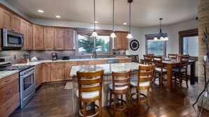 A kitchen with wooden cabinets, a granite countertop, a built-in stove, and a dining area with wooden chairs and a table. - Ridgeview Court Townhome: Incredible Rooftop Deck (Frisco)