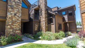 A modern multi-story building with a stone facade, wooden balconies, and a well-maintained garden. - Ridgeview Court Townhome: Incredible Rooftop Deck (Frisco)