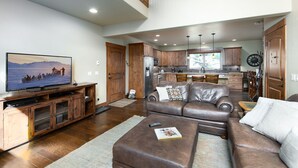 A spacious living room with a large flat-screen TV, leather sofa, and wooden cabinets. - Ridgeview Court Townhome: Incredible Rooftop Deck (Frisco)