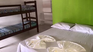 A room with a bunk bed, a single bed with decorative pillows, and a green accent wall. - Chalés Porto Seguro (São Sebastião)