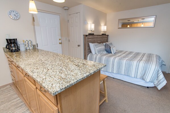 Une chambre compacte comprenant un lit, une petite kitchenette et une salle de bain.