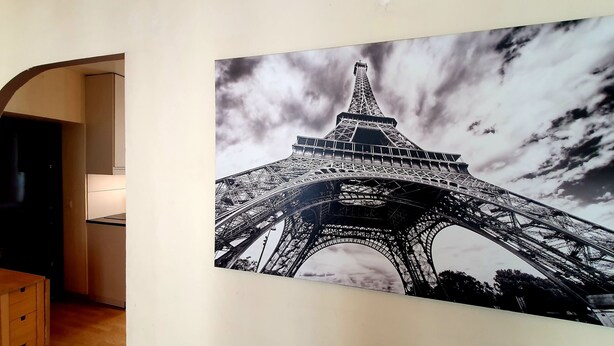 Un couloir orné d’une grande affiche de la Tour Eiffel, d’une armoire en bois et de tableaux encadrés accrochés au mur.