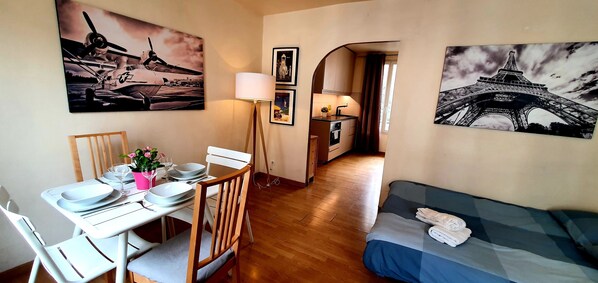 A compact living space with a dining area, kitchenette, and a bed.