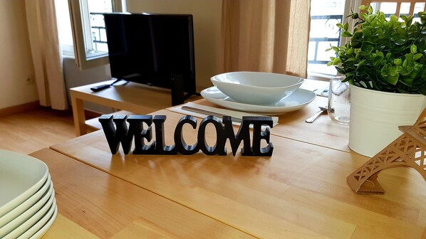 A wooden table with a 'WELCOME' sign, a bowl, a spoon, and a potted plant. - Welcome to Paris - Apartment (Ivry-sur-Seine)
