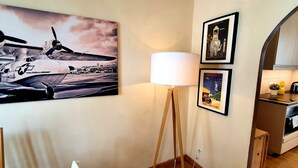 Une cuisine au design moderne, un lampadaire et un grand tableau représentant des avions accroché au mur.