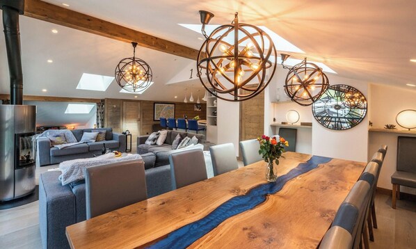 Een modern interieur met een houten eettafel, banken en een open haard.