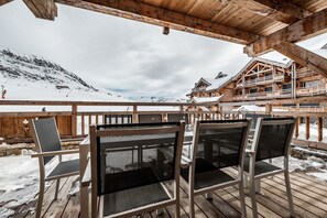 A wooden deck with outdoor seating and a view of a mountain. - WAPA - Premium Ski-in Ski-out Apartment (Huez)