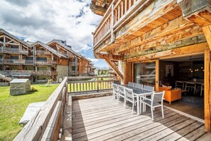 A wooden lodge with a deck, outdoor seating, and a view of the mountains. - WAPA - Premium Ski-in Ski-out Apartment (Huez)