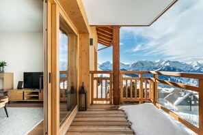 Un balcón de madera con vistas a montañas nevadas.