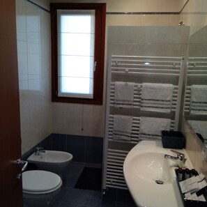 Bathroom features a sink, toilet, and window with a towel rack and storage.