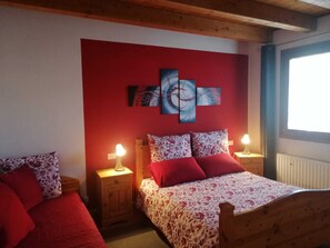Cozy bedroom with a wooden bed frame, red headboard, and floral-patterned bedding.
