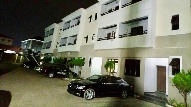 A multi-story building with balconies and a parking area with cars. - Esenyo Luxury Apartments (Abuja)