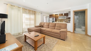 A modern living room with a sectional sofa, a coffee table, and a TV. - Baia Residence 2 - Prata By SCH (São Martinho do Porto)