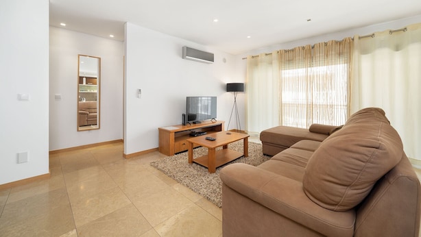 A modern living room with a sofa, a TV, a coffee table, and a lamp. - Baia Residence 2 - Prata By SCH (São Martinho do Porto)