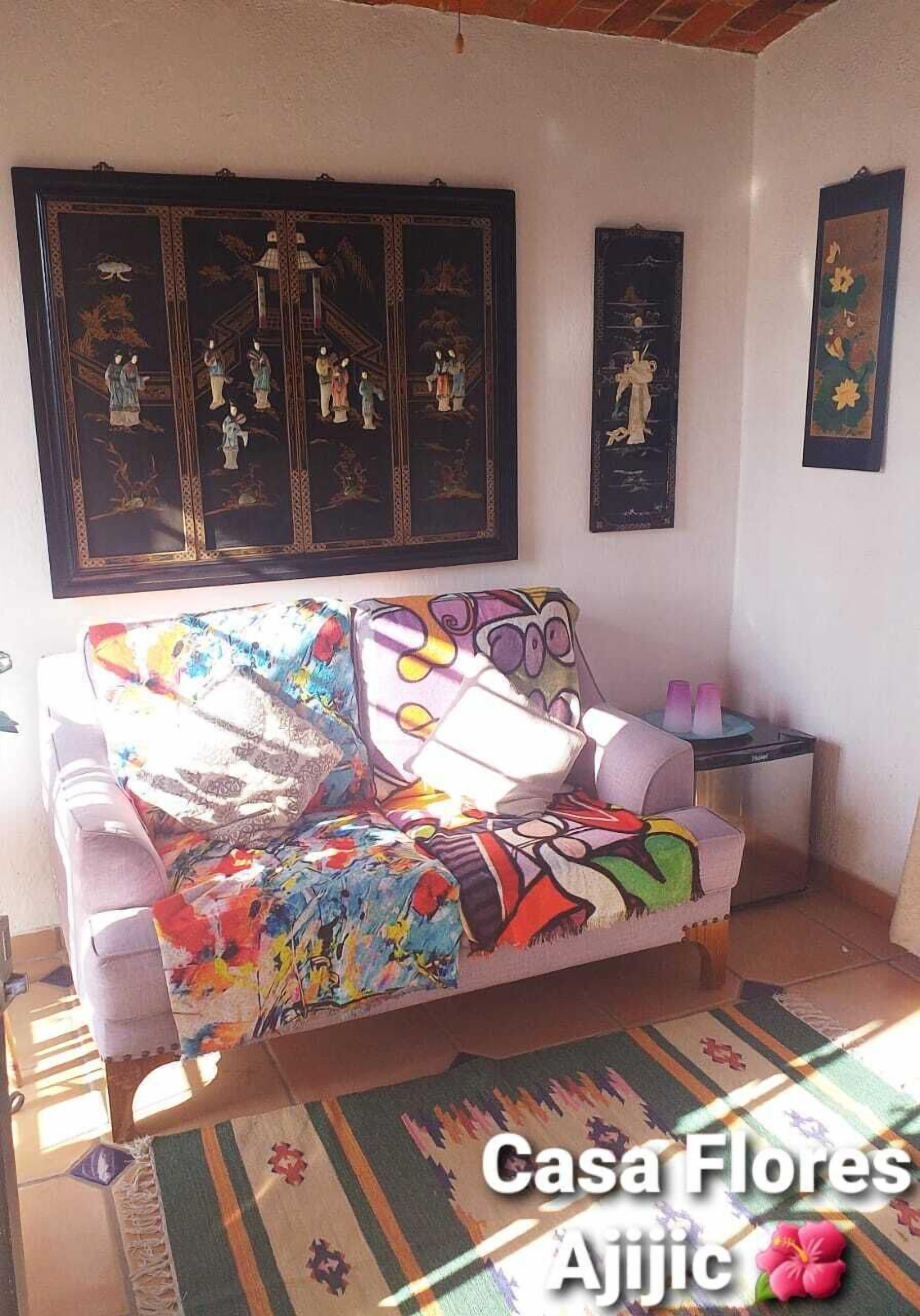 A living room with a colorful sofa, a patterned rug, and traditional artwork on the walls.