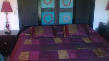 A bedroom with a bed, a nightstand, a lamp, and a wall with a framed picture.