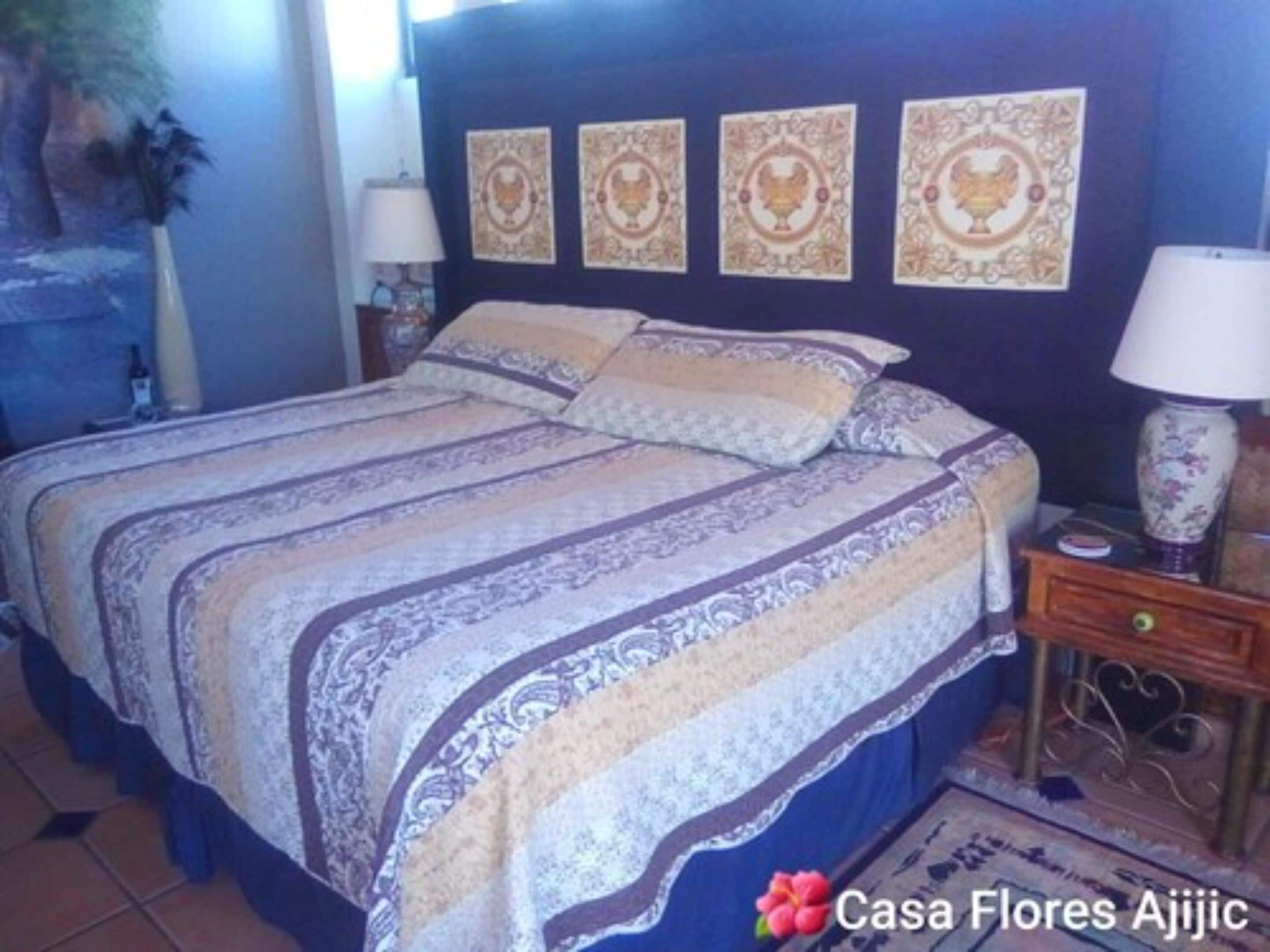 A bedroom with a bed, a nightstand, a lamp, and wall decorations.