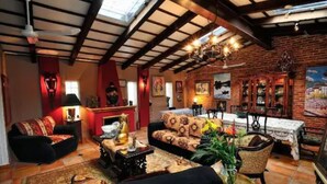 A cozy living room with a fireplace, comfortable seating, and a dining area with a table and chairs. - Casa Flores Bed & Breakfast (Ajijic)
