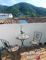 Um terraço com uma mesa, duas cadeiras, um vaso de planta e vista para uma montanha.