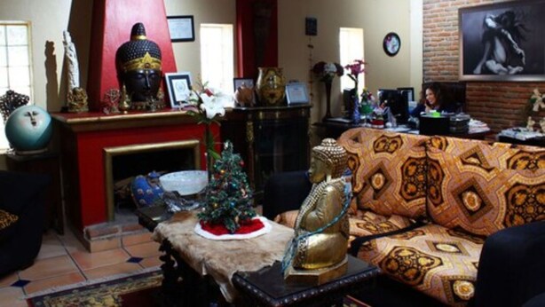 A living room with a fireplace, a Buddha statue, a Christmas tree, and a couch. - Casa Flores Bed & Breakfast (Ajijic)
