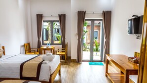 A hotel room with two beds, a desk, a chair, a TV, and a view of the outdoors. - Rainforest Resort Phu Quoc (Phu Quoc)