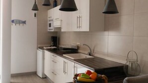 Een moderne keuken met witte kastjes, een donker aanrecht en een hanglamp.